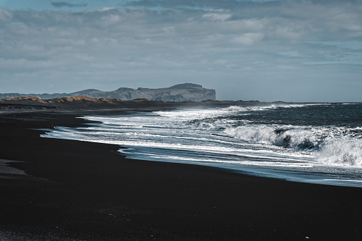 Black sand beach with waves in Vik.