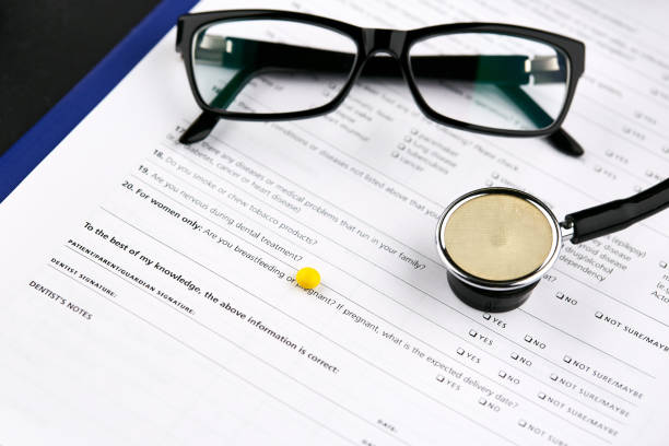 istock Glasses, stethoscope and yellow pill on medical questionnaire fo 1156360309