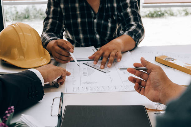 istock engineers pointing to building on blueprint to drawing design building Project in office, construction concept. Engineer concept 1156360437