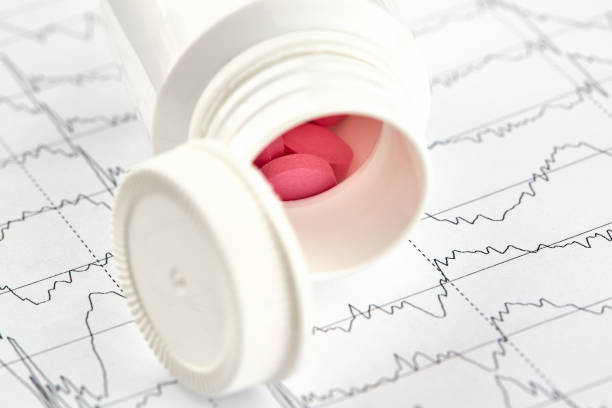 istock Red pills in white vial and EKG graph on background 1156360485