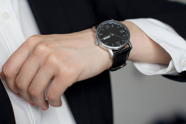 istock young woman in black suit checking time 1156370343
