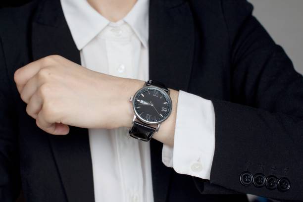 istock young woman in black suit checking time 1156370524