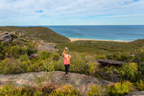 mujer en las vistas de acantilado al océano, sosteniendo el teléfono móvil - australian culture hiking australia people fotografías e imágenes de stock