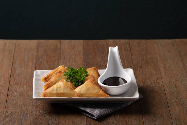 istock Delicios dish, Fried samosas in white plate with chocolate dipping sauce on wooden table background 1156378884