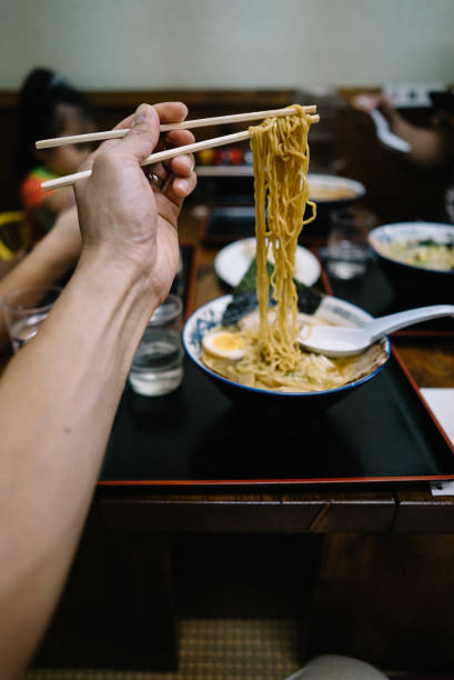 istock A man holds noodles in front of him with chopsticks 1156379745