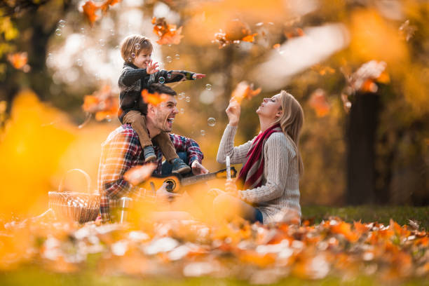 jeune famille insouciante ayant l'amusement sur le pique-nique dans le jour d'automne dans la nature. - bubble wand outdoors little boys mother photos et images de collection