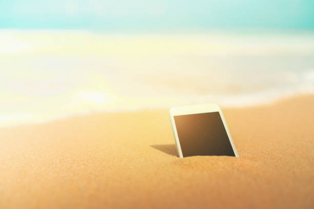 istock Smartphone on sand tropical summer beach on vacation day texture background. 1156395931