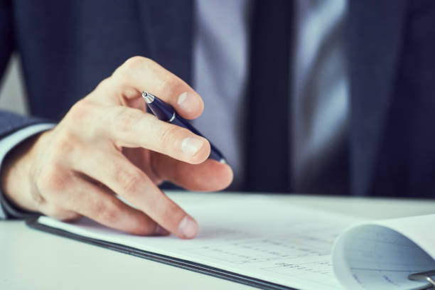 istock Businessman in suit making notes on a notebook. Business man working at office desk. 1156396223
