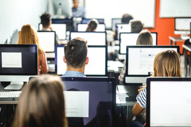 istock Back view of group of students on a class at computer lab. 1156396327
