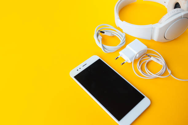 Mobile kit with smartphone, headphones and chargers. Mobile kit with smartphone, headphones and chargers. Yellow background, Copy space to the left personal accessory stock pictures, royalty-free photos & images