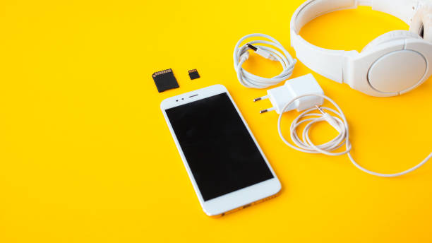 Mobile kit with smartphone, headphones and chargers. Mobile kit with smartphone, headphones and chargers. Yellow background kruis stock pictures, royalty-free photos & images