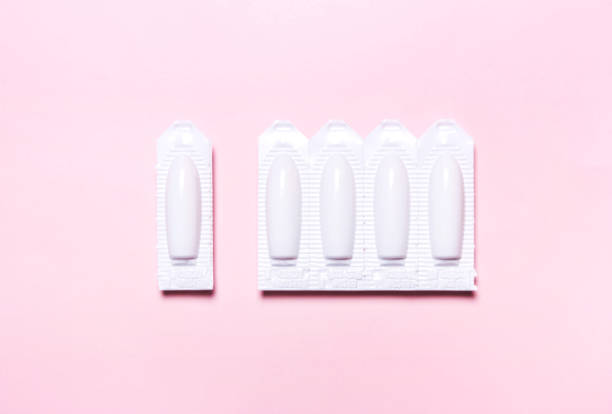 медицинский, вагинальный суппозиторий на розовом фоне, для лечения геморроя - vagina contraceptive gynecologist doctor стоковые фото и изображения