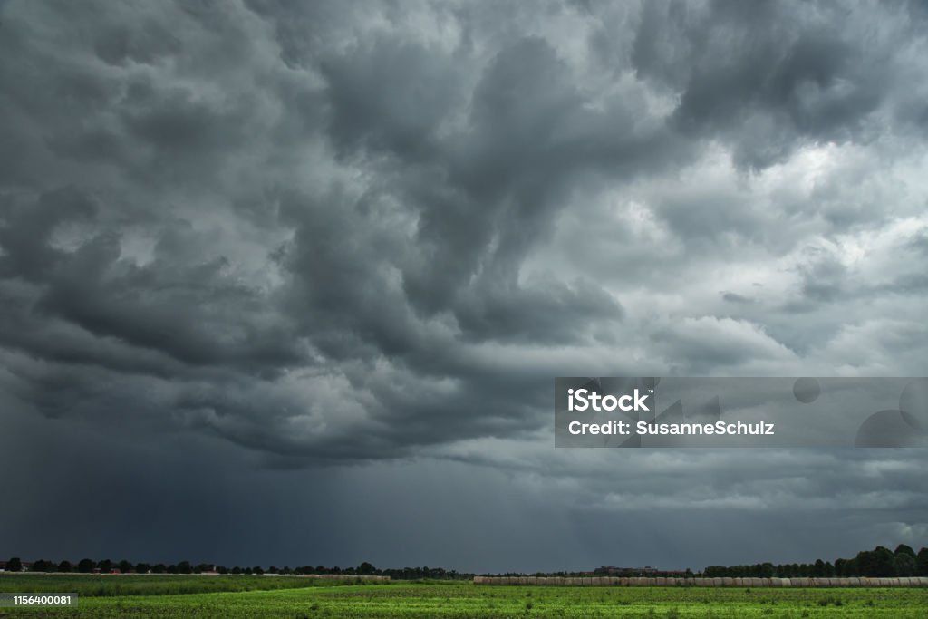 threatening storm clouds over farmland Dark, threatening clouds move over a summery, rural landscape and bring heavy rain with thunderstorms. Storm Cloud Stock Photo