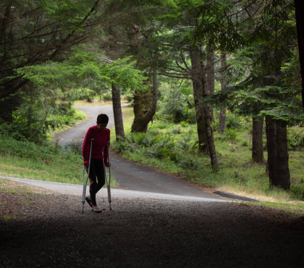 istock Woman walking on crutches uphill in nature 1156400321