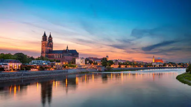 Panoramic cityscape image of Magdeburg, Germany with reflection of the city in the Elbe river, during sunset.