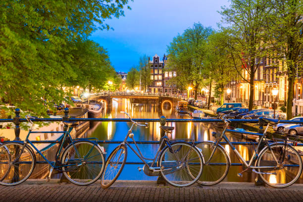 istock Old bicycles on the bridge in Amsterdam, Netherlands against a canal during summer twilight sunset. Amsterdam postcard iconic view. Tourism concept. 1156409411