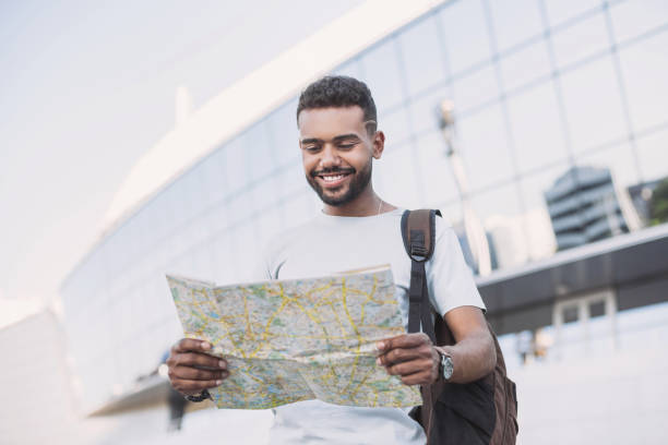 istock Young man looking at travel map in a city 1156414721