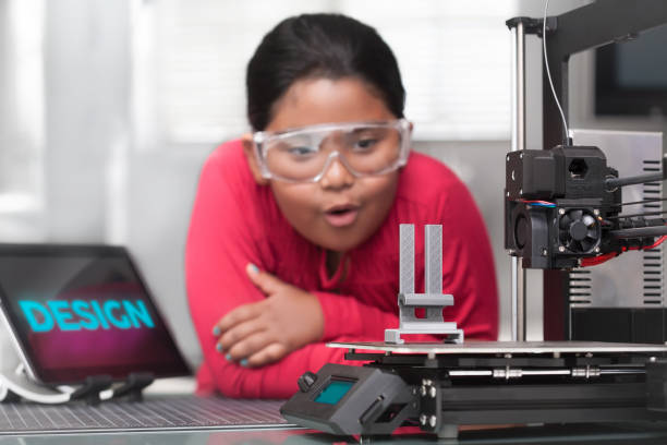 An young hispanic girl is amazed as she looks at her 3d printed project in a STEM summer class. An young hispanic girl is amazed as she looks at her 3d printed project in a STEM summer class. 3d printing hand stock pictures, royalty-free photos & images