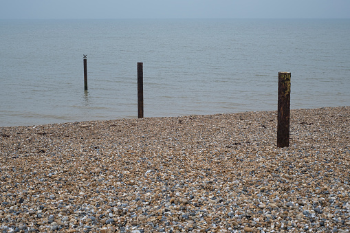 Pebble beach and row of rusty posts in the sea, Thanet Kent