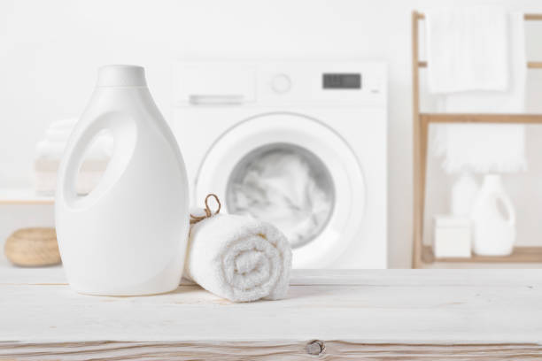 Plain detergent bottle on wood over defocused laundry room interior Plain detergent bottle on wood over defocused laundry room interior laundry detergent stock pictures, royalty-free photos & images