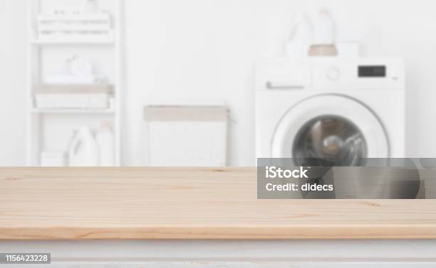 Wooden Table In Front Of Defocused Washing Machine And Laundry Stock Photo - Download Image Now