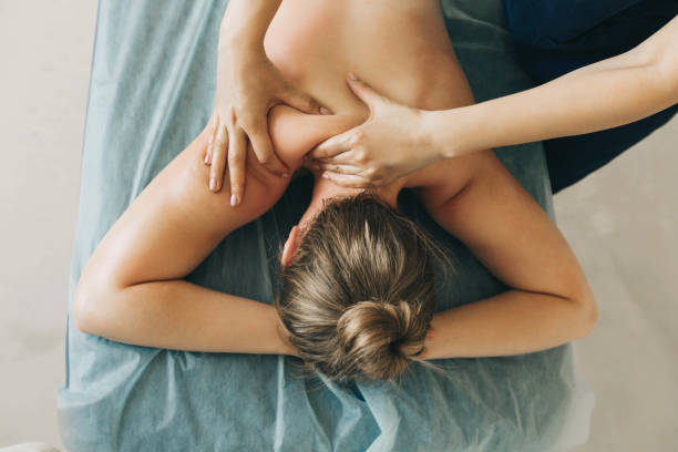 joven rubia recibiendo un masaje de espalda en un centro médico. - beautiful healthy lifestyle caucasian recovery fotografías e imágenes de stock