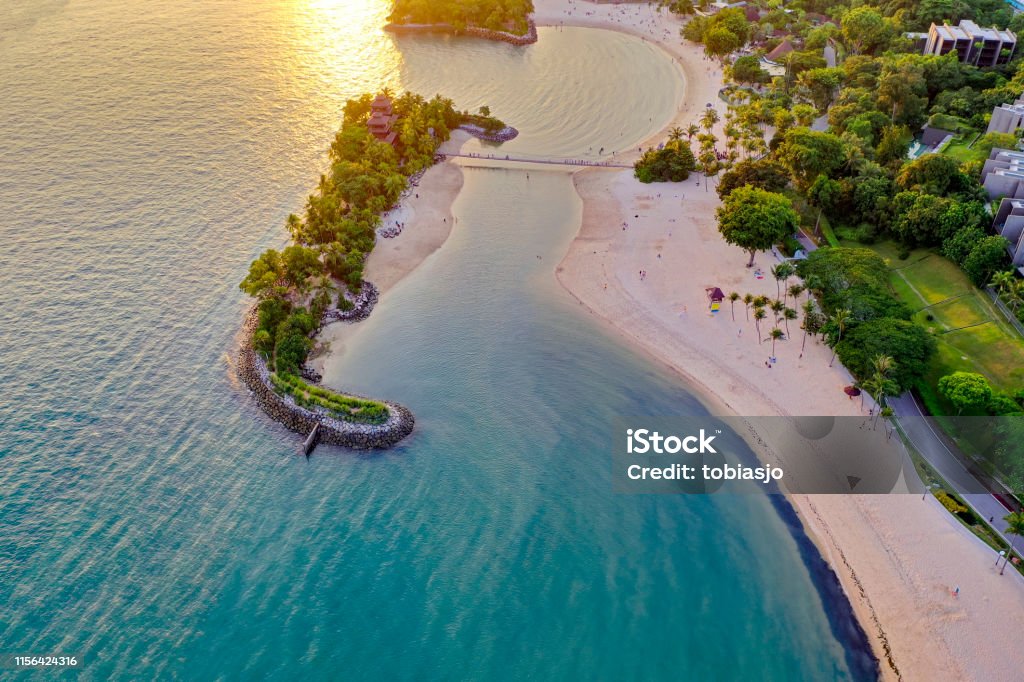 Sentosa Beach in Singapore at sunset The tropical island of Sentosa in Singapore have many beautiful beaches and is surrounded by the Pacific Ocean and lush rainforest. Here seen at sunset. Sentosa Island Stock Photo