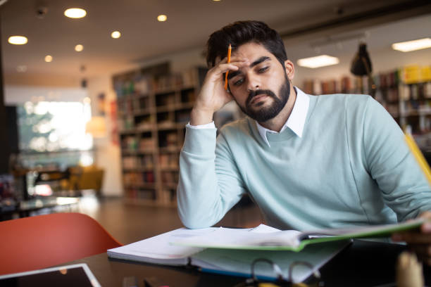 istock People, education, studying, exams and school concept - tired student learning in library 1156424851