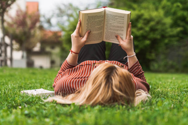 istock Student reading a book and relaxing in the park on a sunny day 1156426149