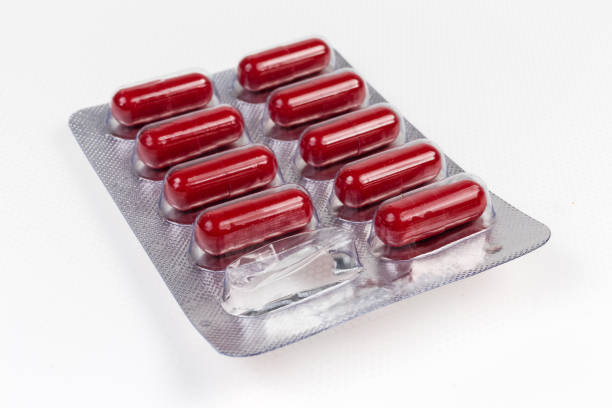 istock Blister pack with red brown capsules pills on light surface 1156426172