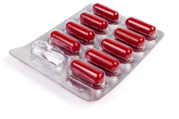 istock Blister pack with red brown capsules pills on light surface 1156426194