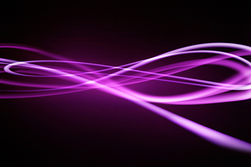 photograph of light streaming on a black background in swirls and waves implying flow and data transfer through broadband and generic other technology.