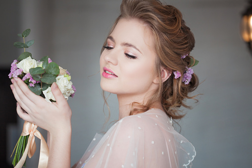 Cute young bride in pink dress. Girl with a wedding bouquet, close-up portrait