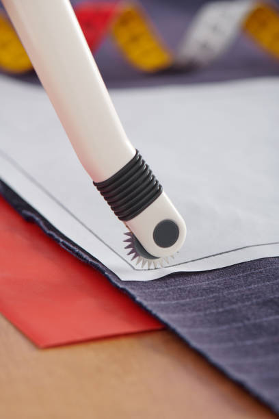 istock Tracing wheel on sewing pattern, red transfer paper under fabric, sewing equipment 1156427534