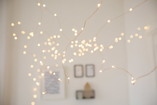Pretty fairy light garland hanging in cozy room for Christmas celebration