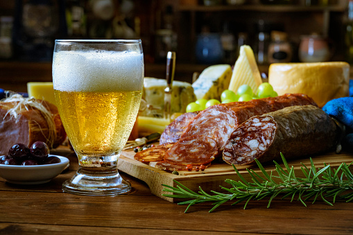 Tapas of cheese, cured ham, salami, beer and chorizo on a rustic wooden table