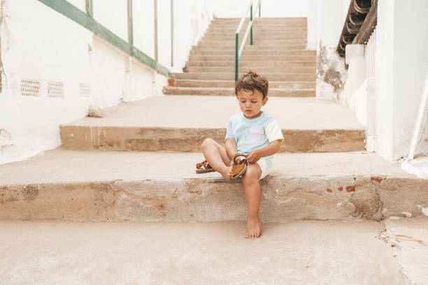 istock Boy putting on shoes after a day at the beach 1156430042