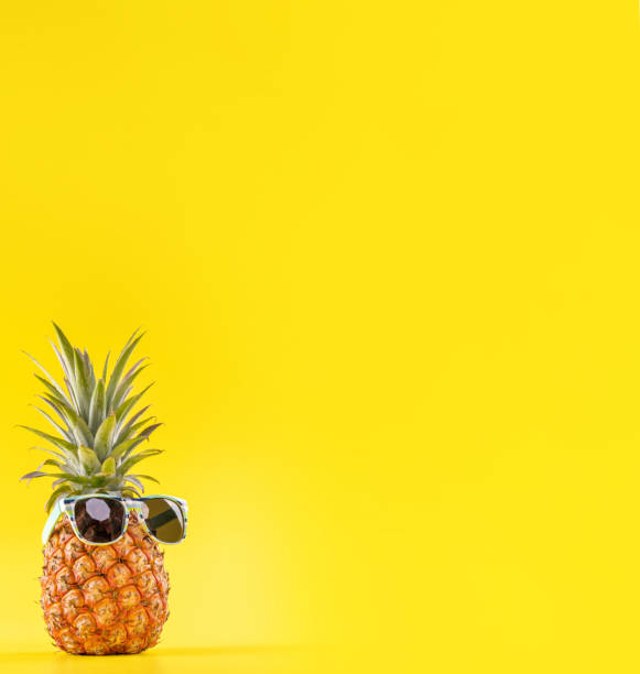 istock Creative pineapple looking up with sunglasses and shell isolated on yellow background, summer vacation beach idea design pattern, copy space close up 1156431369