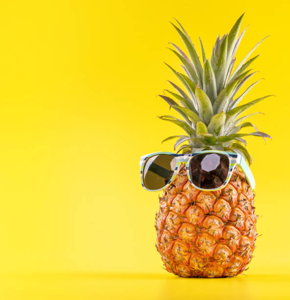istock Creative pineapple looking up with sunglasses and shell isolated on yellow background, summer vacation beach idea design pattern, copy space close up 1156431392