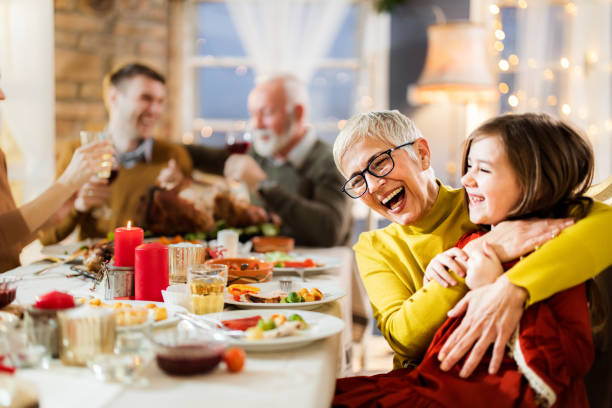 Cheerful grandmother and granddaughter having fun at dining table.