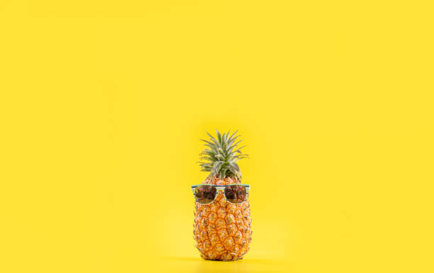 istock Creative pineapple looking up with sunglasses and shell isolated on yellow background, summer vacation beach idea design pattern, copy space close up 1156431454
