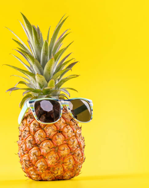 istock Creative pineapple looking up with sunglasses and shell isolated on yellow background, summer vacation beach idea design pattern, copy space close up 1156431566