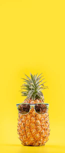 istock Creative pineapple looking up with sunglasses and shell isolated on yellow background, summer vacation beach idea design pattern, copy space close up 1156431800