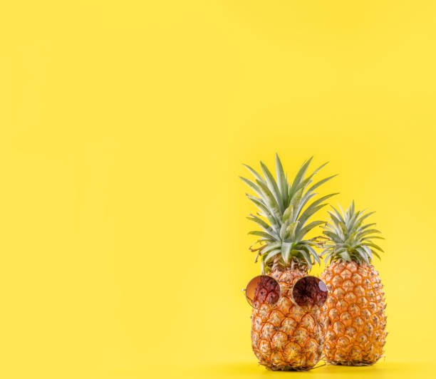istock Creative pineapple looking up with sunglasses and shell isolated on yellow background, summer vacation beach idea design pattern, copy space close up 1156432052