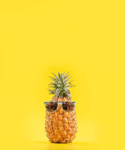 istock Creative pineapple looking up with sunglasses and shell isolated on yellow background, summer vacation beach idea design pattern, copy space close up 1156432117