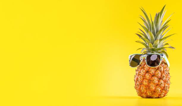istock Creative pineapple looking up with sunglasses and shell isolated on yellow background, summer vacation beach idea design pattern, copy space close up 1156432217