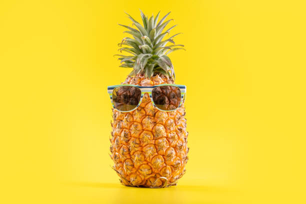 istock Creative pineapple looking up with sunglasses and shell isolated on yellow background, summer vacation beach idea design pattern, copy space close up 1156432297