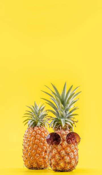 istock Creative pineapple looking up with sunglasses and shell isolated on yellow background, summer vacation beach idea design pattern, copy space close up 1156432365