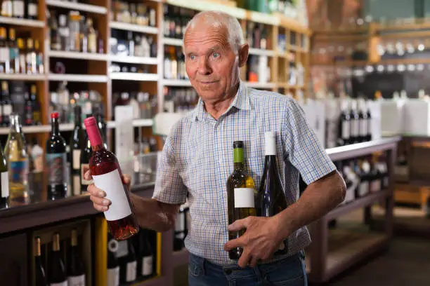 Mature male visiting winehouse in search of bottle of good wine