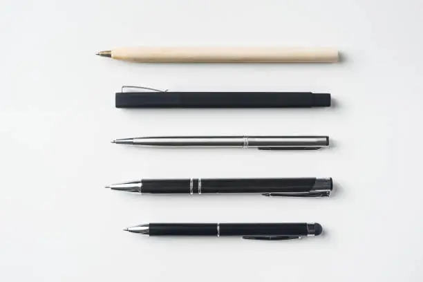 Photo of Top view of collection of pens on white background